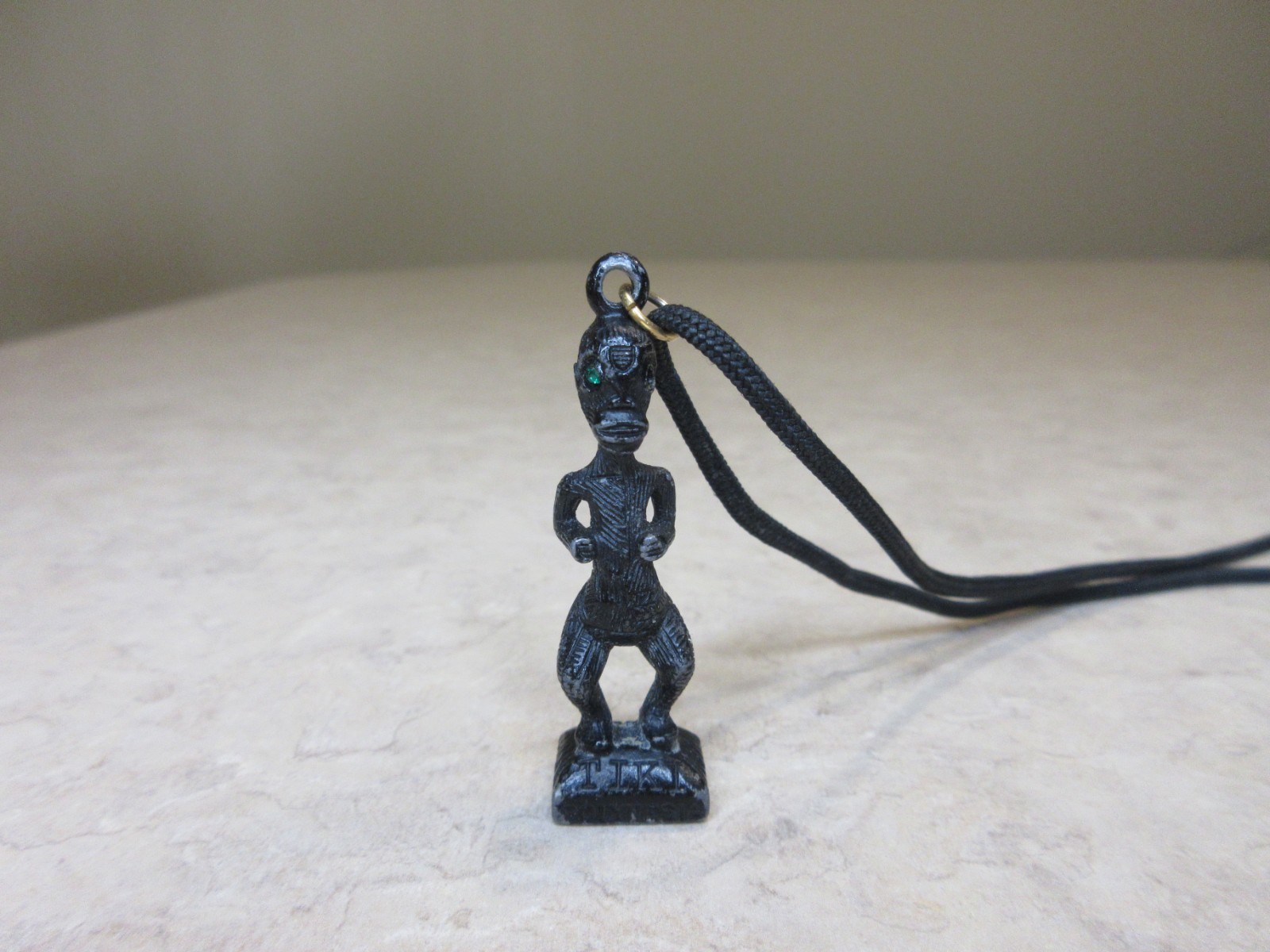 Vintage Metal Tiki Figurine Pendant From Polynesia. Black with green gem eye
