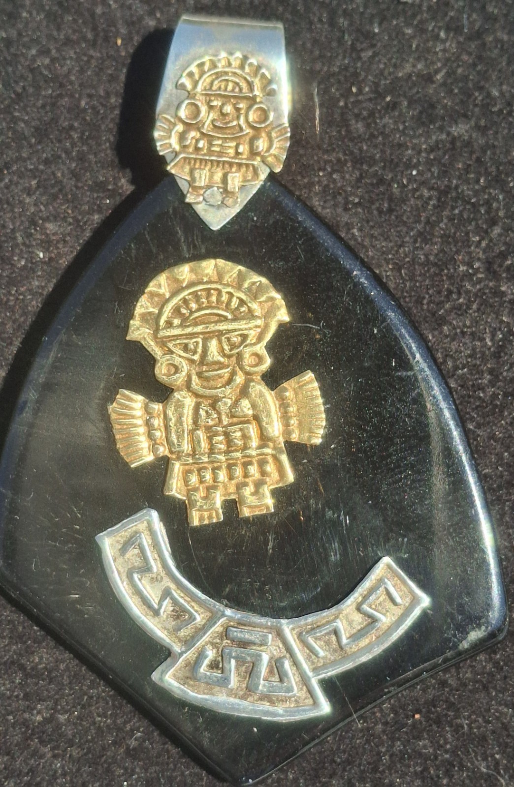 Vintage 18k gold & 925 Peruvian Tumi Deity Pendant on black plastic.
