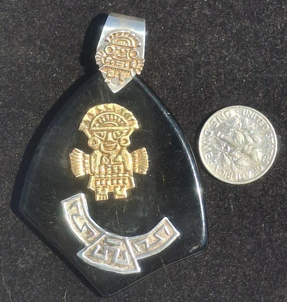 Vintage 18k gold & 925 Peruvian Tumi Deity Pendant on black plastic.