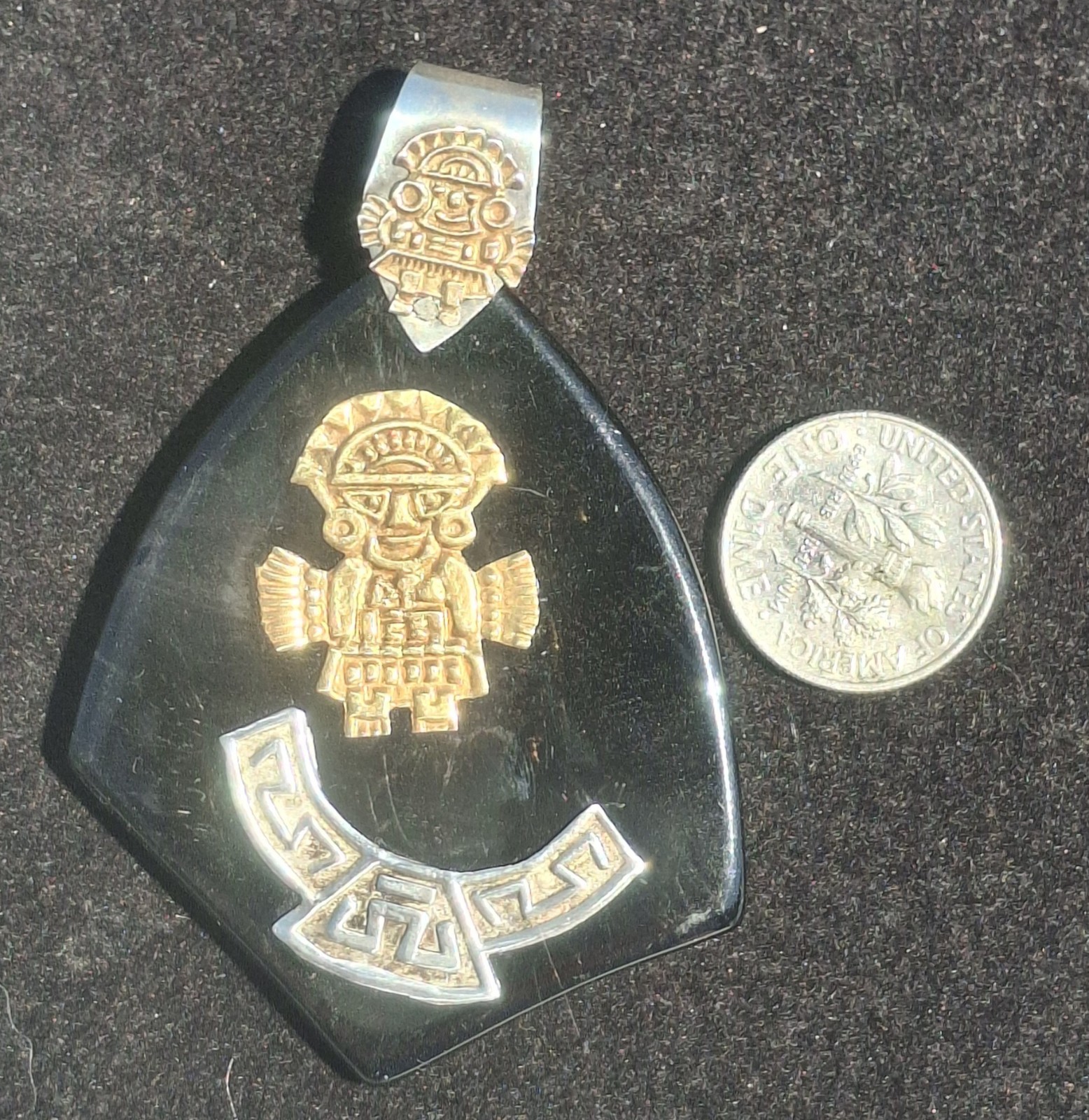 Vintage 18k gold & 925 Peruvian Tumi Deity Pendant on black plastic.